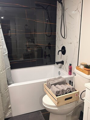 Une salle de bain moderne équipée d’une baignoire, d’une douche et de toilettes.