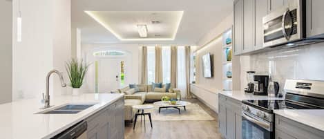 A modern kitchen with a dishwasher, stove, and a dining area with a sofa and coffee table.