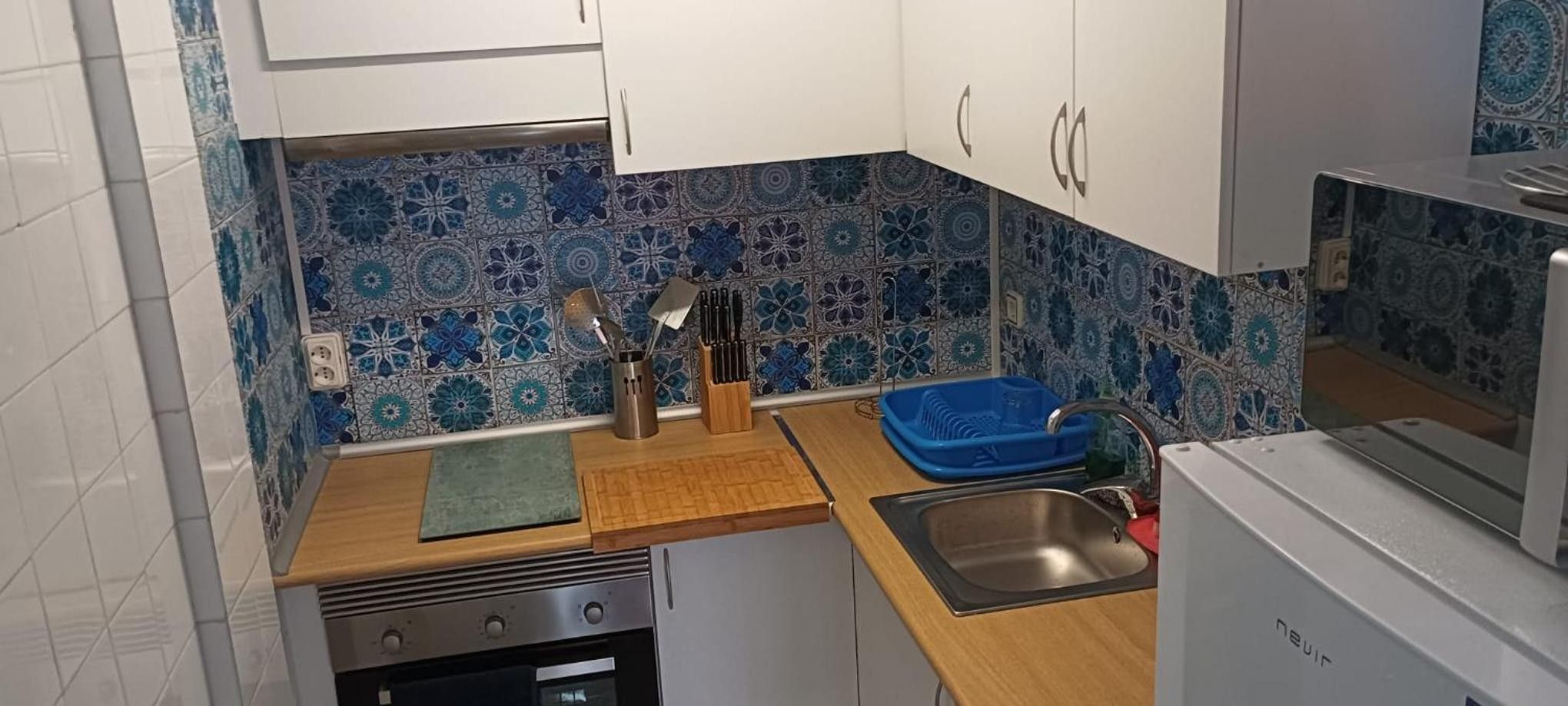 Una cuina compacta amb un rentatge, fogó i armaris.
