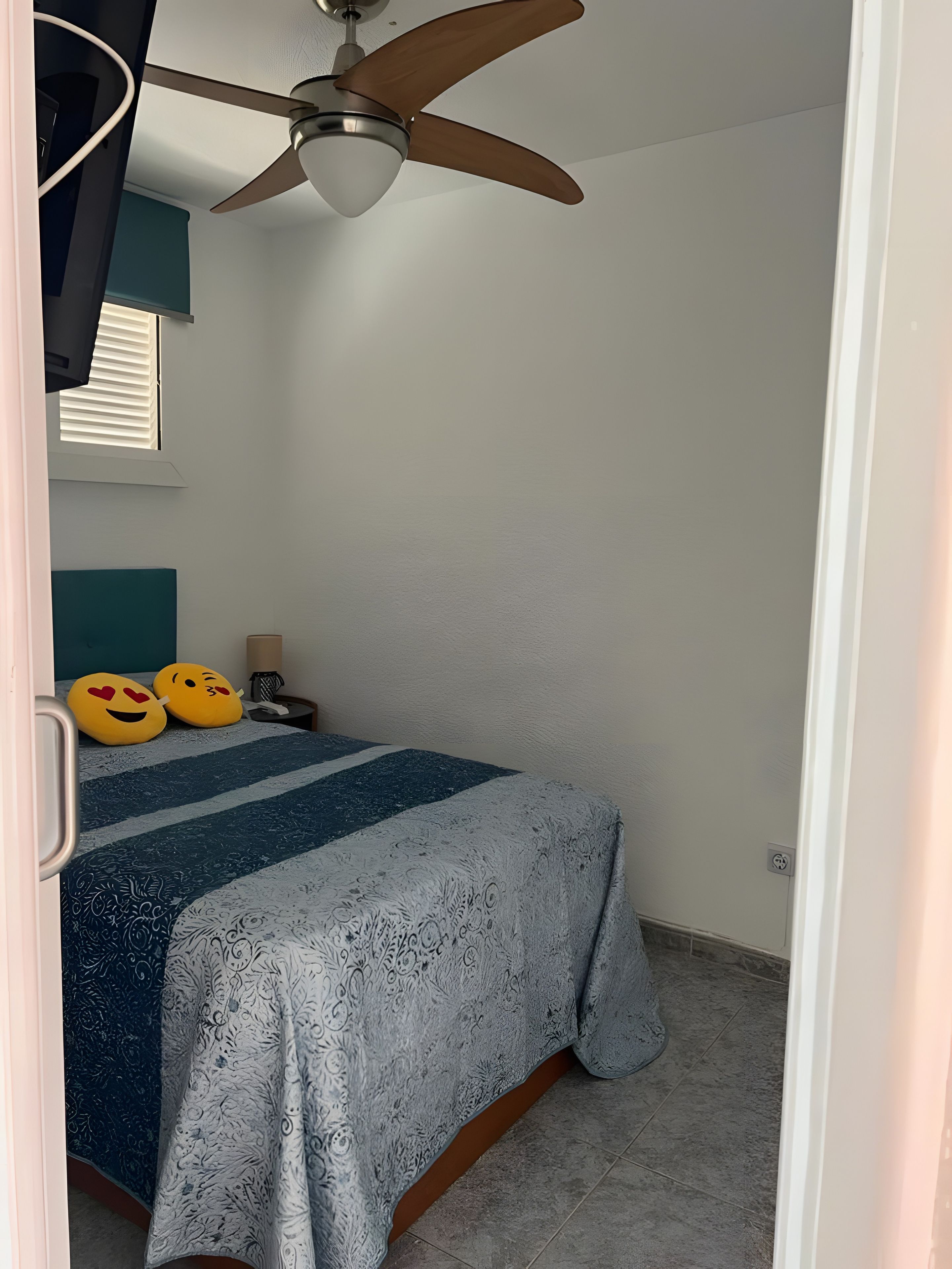 Un dormitori amb llit, almoines, ventilador de sostre i finestra.