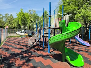 A playground with a green slide and a red and black checkered ground. - Konstanzer 2 - Cozy Apt - Palas Mall  (Iași)