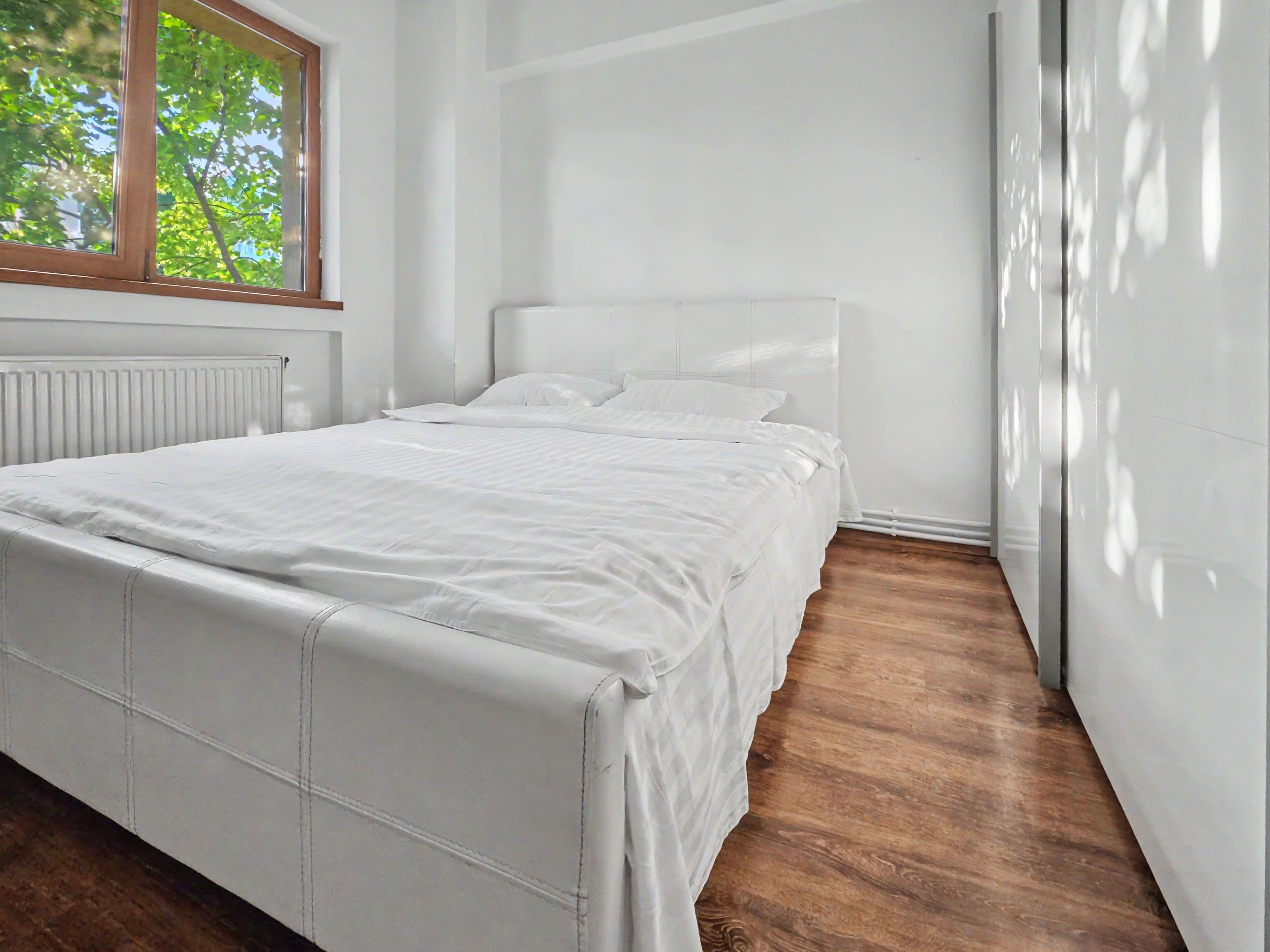 Una camera da letto moderna con un letto grande, un termosifone e una finestra.