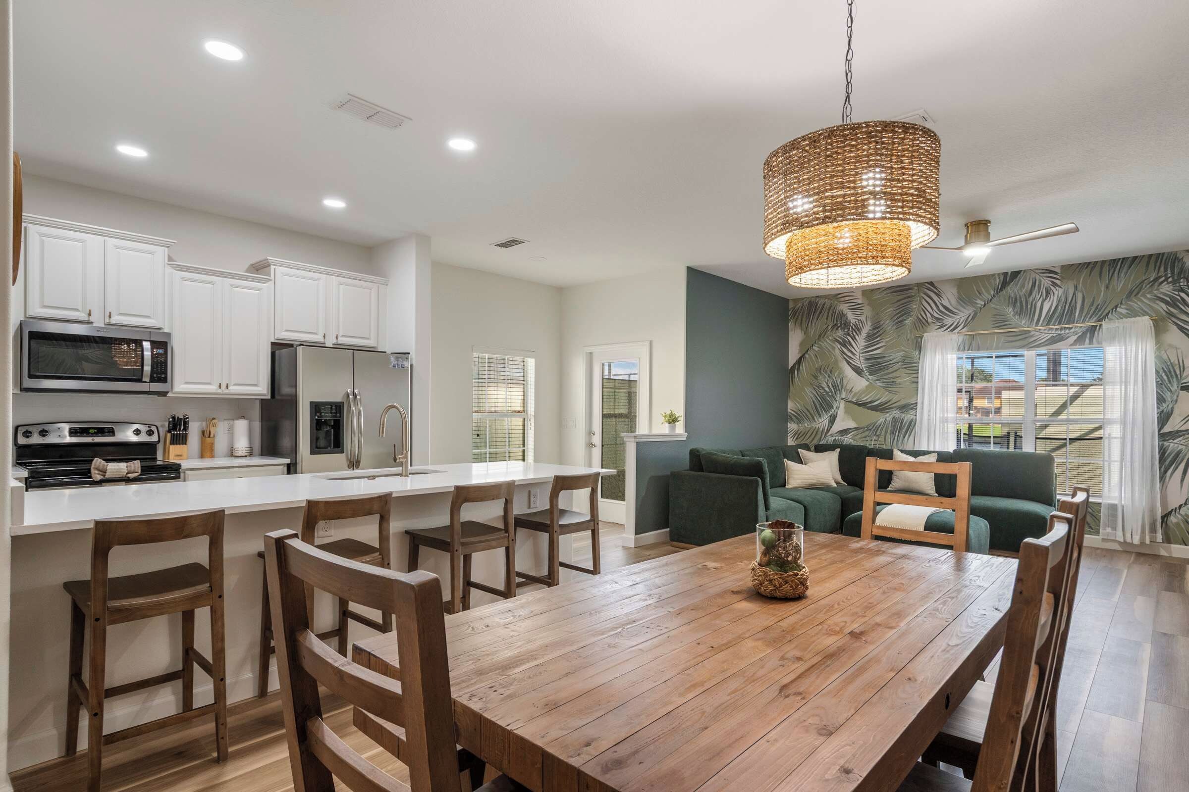 A modern kitchen with white cabinets, a built-in microwave, and a stainless steel refrigerator.