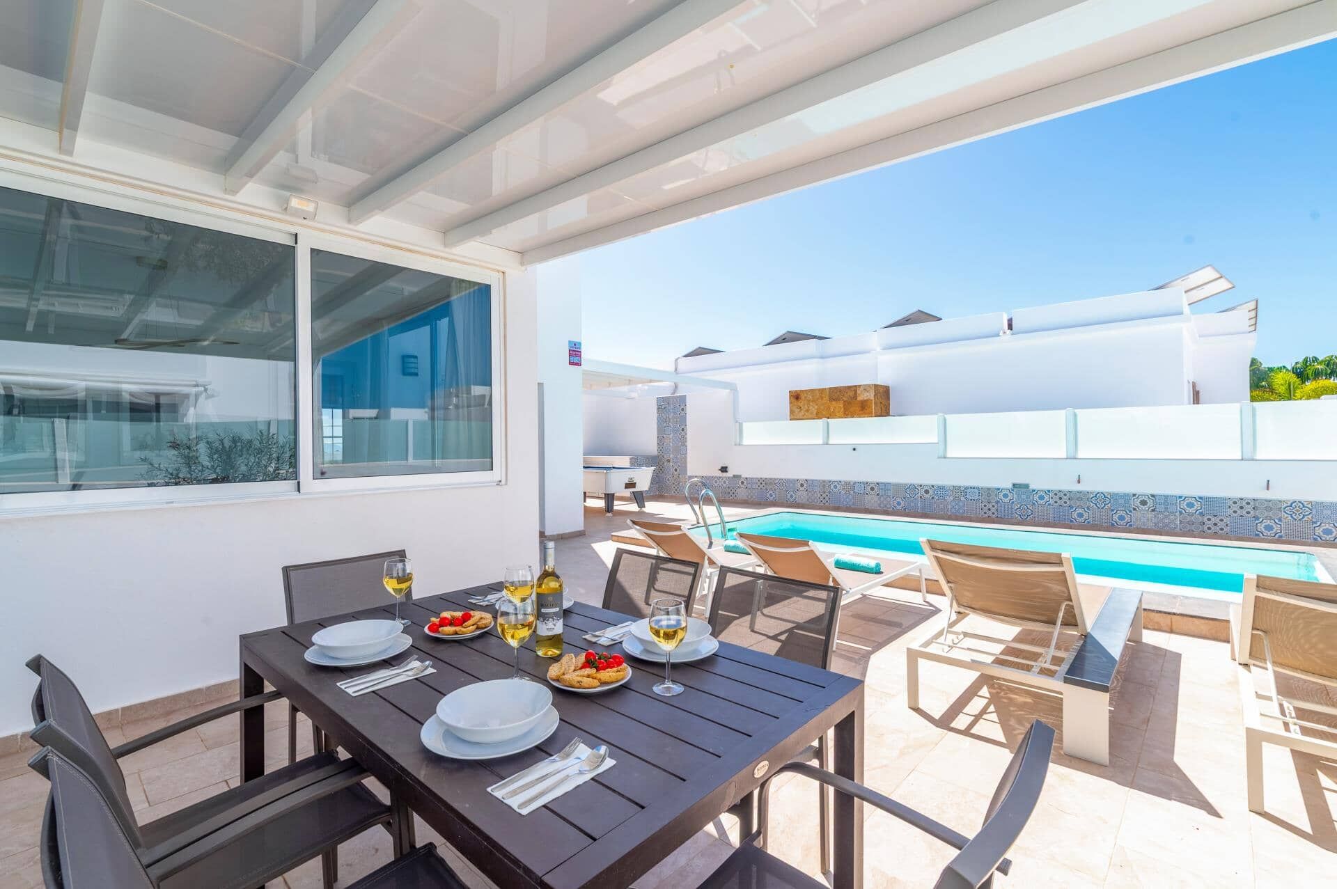 Un espace extérieur aménagé pour les repas, avec une piscine, un coin salon couvert et une vue sur la piscine.