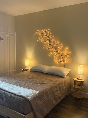 A bedroom with a bed, two bedside tables, and a wall-mounted light fixture.