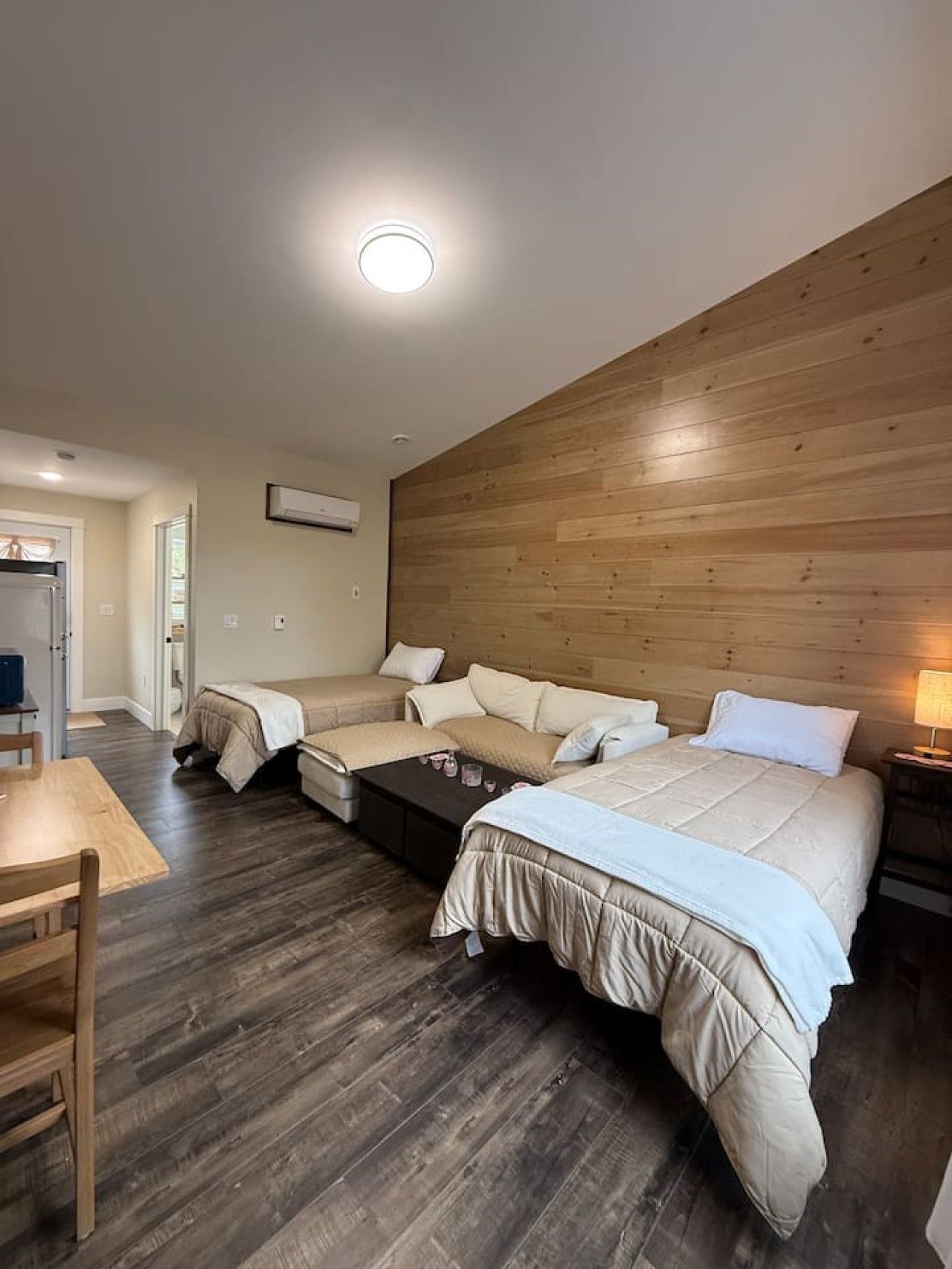 Une chambre d’hôtel avec une tête de lit en bois, un lit, un canapé, une table basse et un bureau.