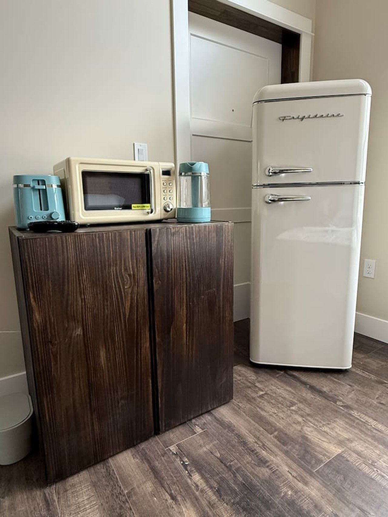 A kitchen with a white refrigerator, a wooden cabinet, and a microwave on top.