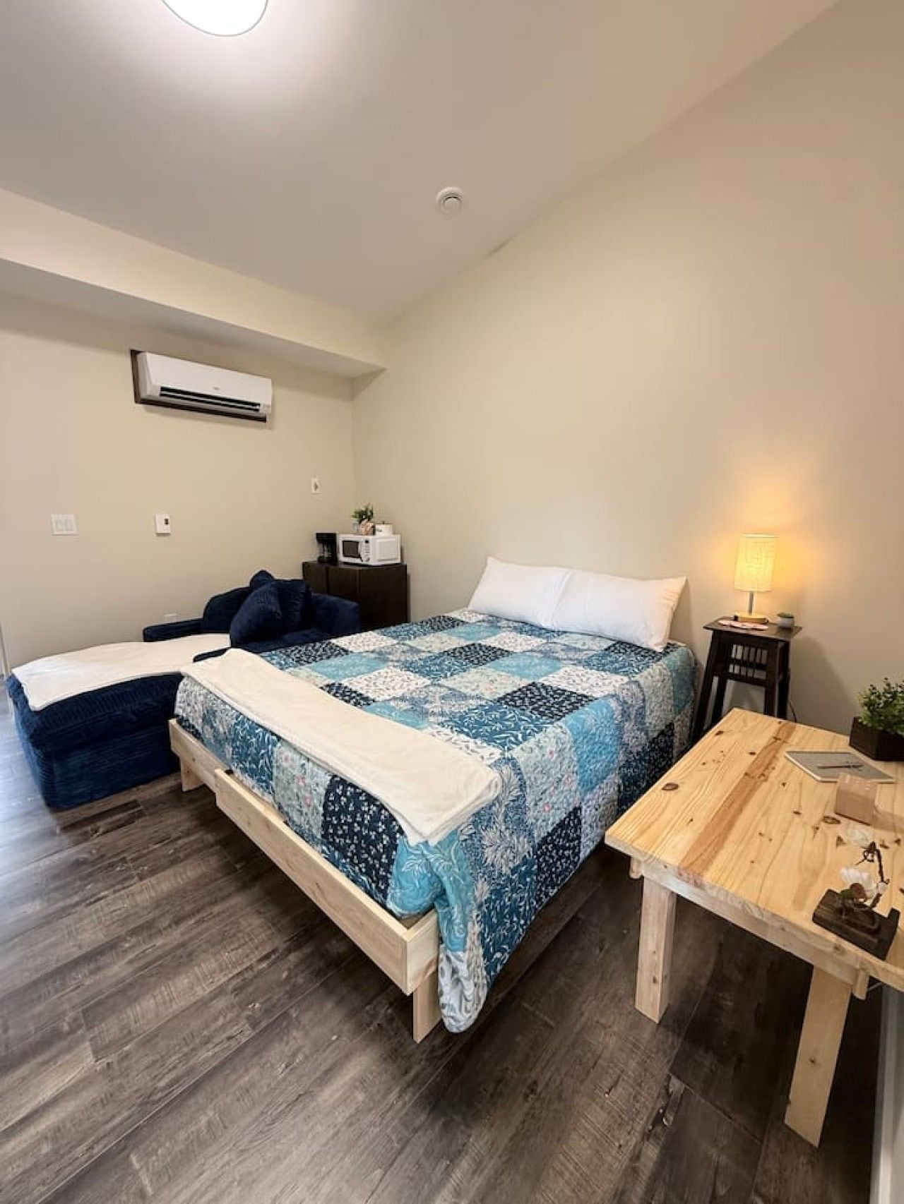 Una camera da letto con un letto, un comodino, una lampada e un condizionatore d'aria.
