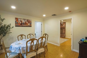 A dining area with a round table set for four, wooden chairs, and a painting on the wall. - Spacious 5-bedroom house in delightful Fountain Valley with AC (Fountain Valley)