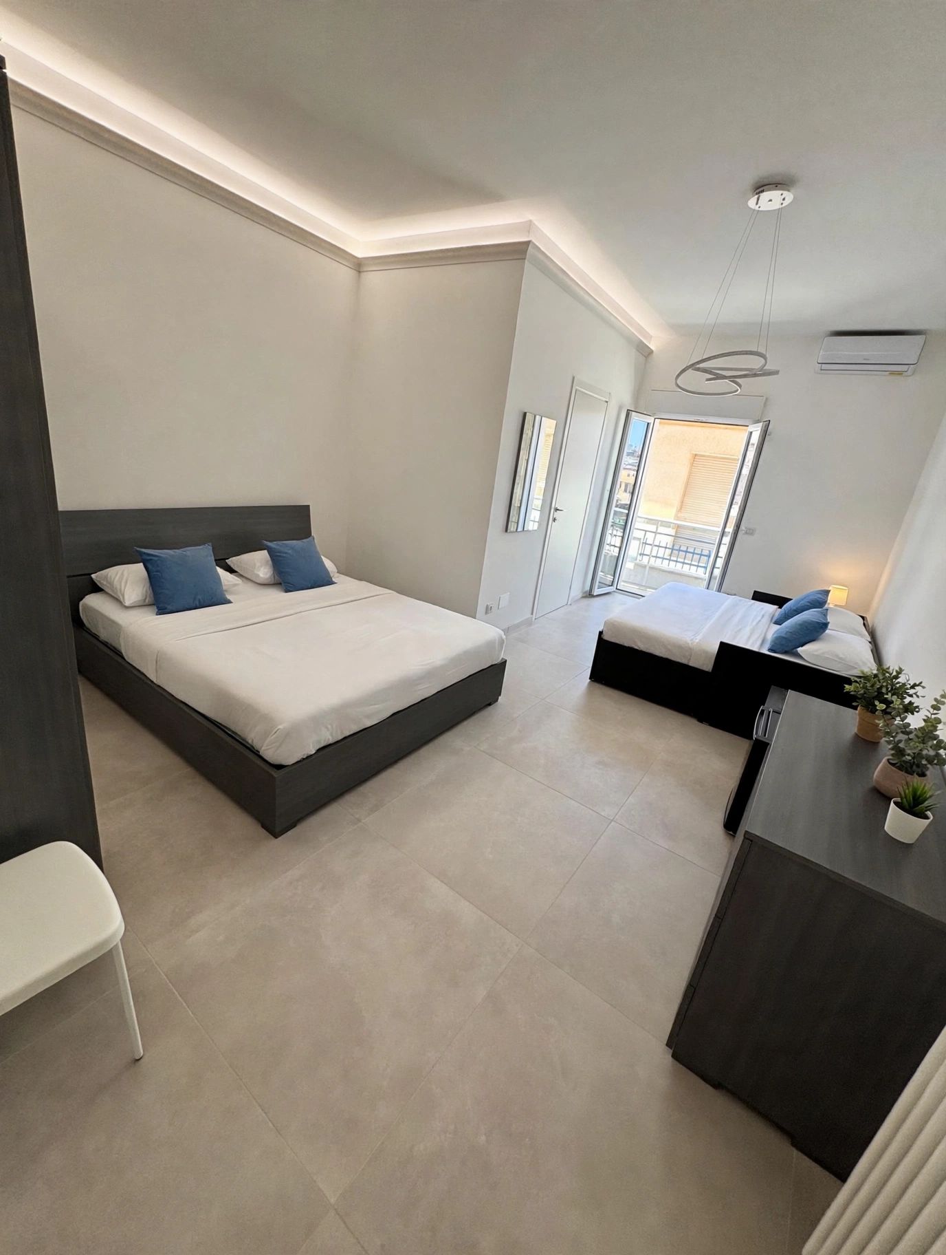 Un dormitorio moderno con una cama grande, un escritorio pequeño y un balcón.