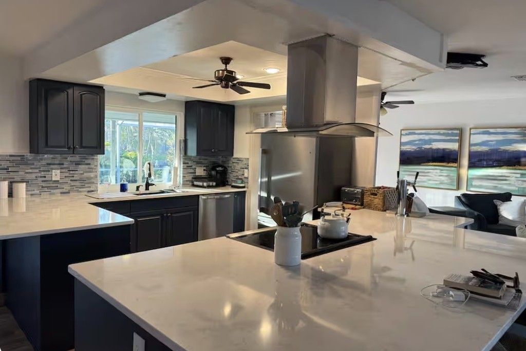 Una cocina moderna con armarios oscuros, una isla grande y vistas al exterior.