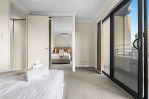 Une chambre d’hôtel comprenant un lit, une salle de bain et une porte-fenêtre coulissante donnant sur un balcon.