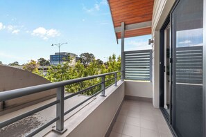Un balcó amb barana metàl·lica, vista a un paisatge urbà i un edifici amb un disseny modern.