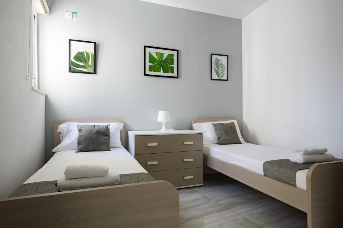Ein Hotelzimmer mit zwei Betten, einem Nachttisch und Wandbildern.