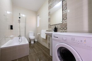Ein Badezimmer mit Badewanne, Toilette, Waschbecken und Waschmaschine.