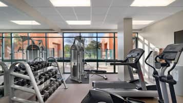 Ein Fitnessstudio mit Laufbändern, Kurzhanteln und Kraftgeräten.