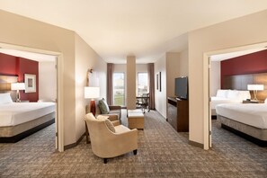 A hotel room with two beds, a desk, a chair, a TV, and a view of the outdoors. - Spacious 2BR Suite w/ Free Daily Breakfast + Pool (San Antonio)