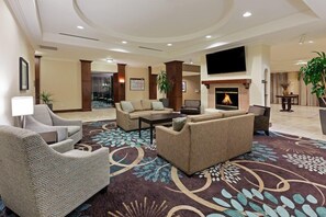 Un hall d’hôtel doté d’une cheminée, de canapés, de fauteuils et d’un grand téléviseur à écran plat.