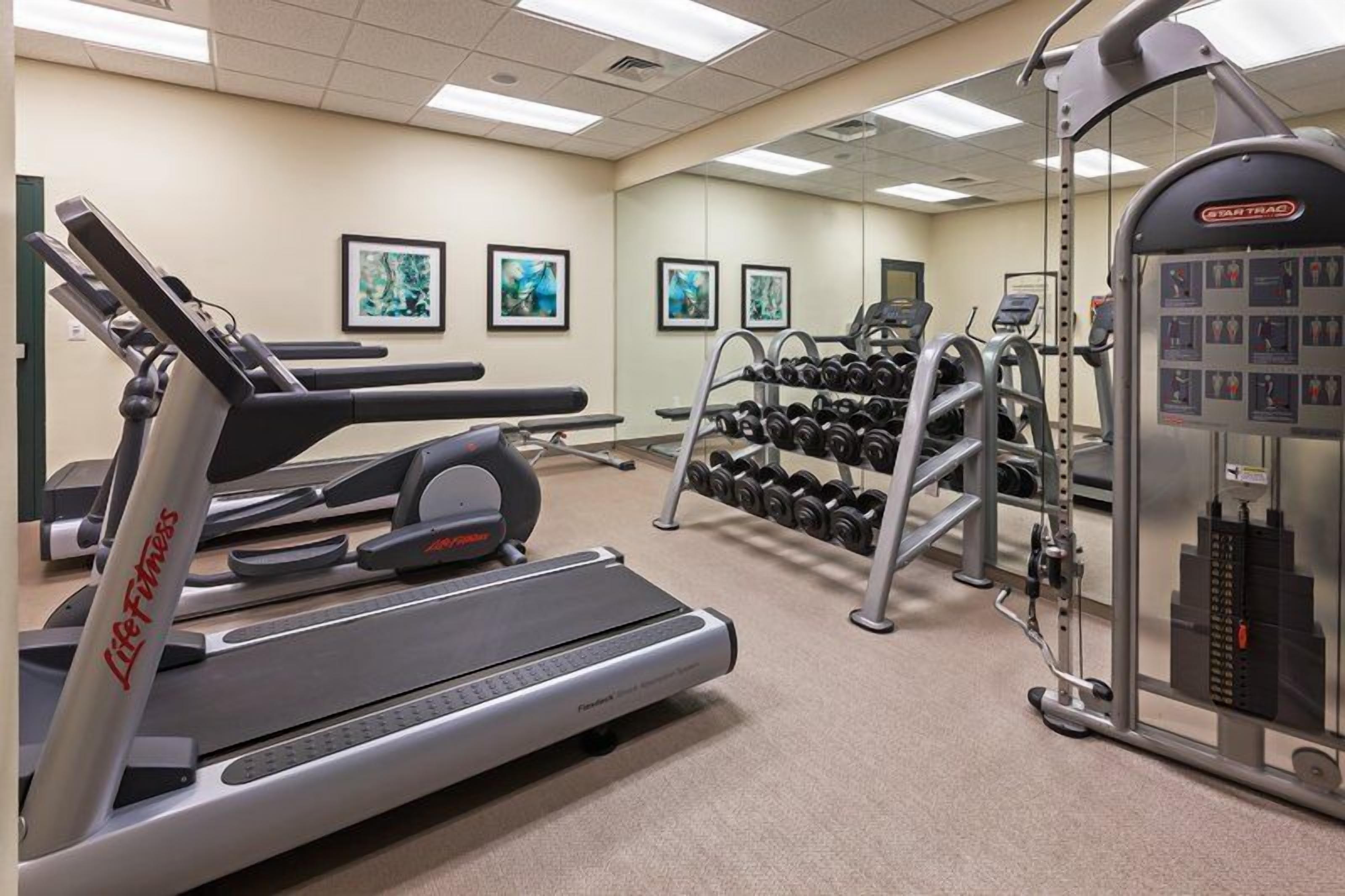 A gym with cardio equipment, weight machines, and dumbbells.