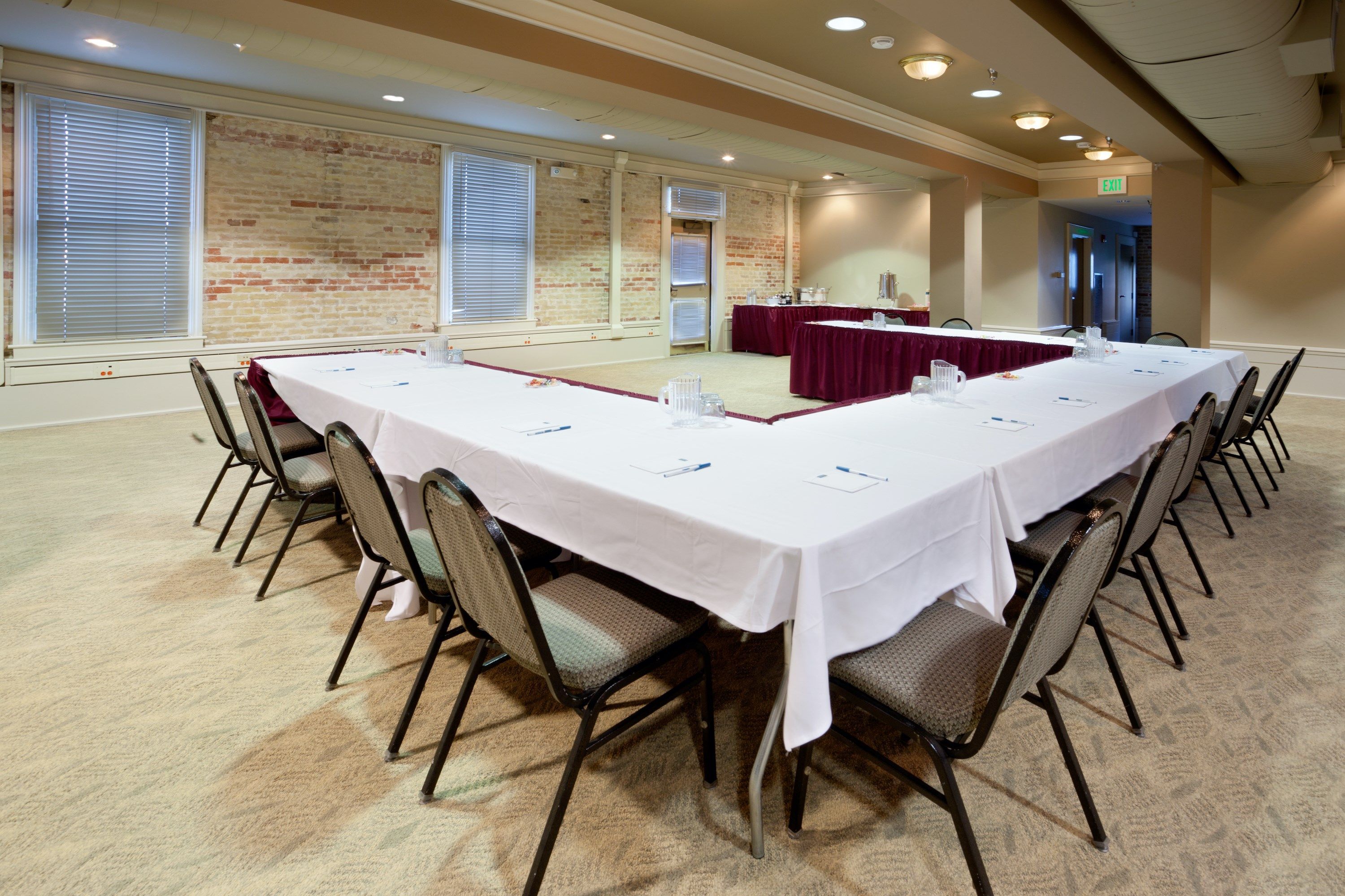 Une salle de conférence avec une longue table, des chaises et un mur en briques.