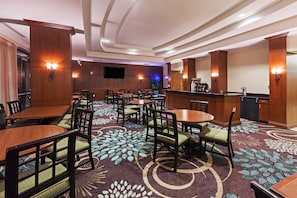 A hotel lobby with multiple dining tables and chairs, a bar area, and a patterned carpet. - City View Studio w/ 2 Queen | Hot Breakfast + Pool (San Antonio)