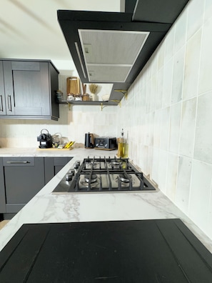 A modern kitchen with a gas stove, dark cabinets, and a white tiled backsplash.