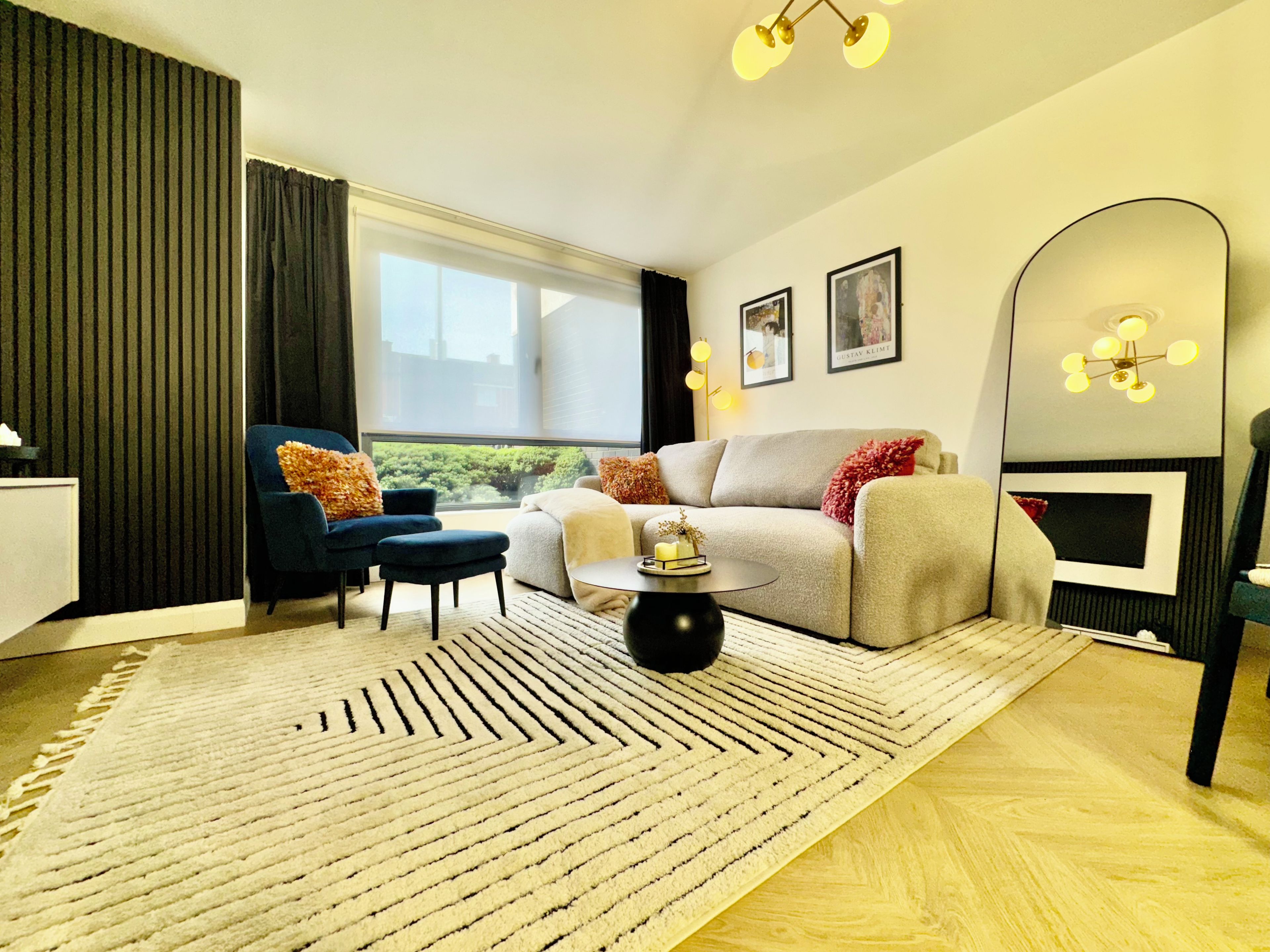 Ein modernes Wohnzimmer mit einer Couch, Sesseln, einem Couchtisch und einem großen Spiegel.