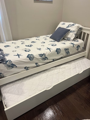 A single bed with a white frame and a patterned bedspread. - ENJOY THE COMFORTS OF HOME IN THIS MODERN 6 ROOM CONDO. 1/4 BLOCK TO BEACH! (Seaside Park)