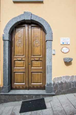 Una puerta doble de madera con un arco de piedra, una placa y una pequeña placa de piedra en la pared.