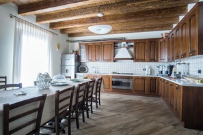 Een moderne keuken met houten kastjes, een centraal eiland en een eethoek met stoelen.