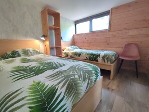 Ein Schlafzimmer mit einem Bett, einem Holzregal, einem Stuhl und einem Fenster.