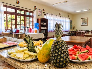 A buffet with various fruits and a pineapple centerpiece.