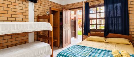 A room with a bunk bed, a single bed, a television mounted on the wall, and a ceiling fan.