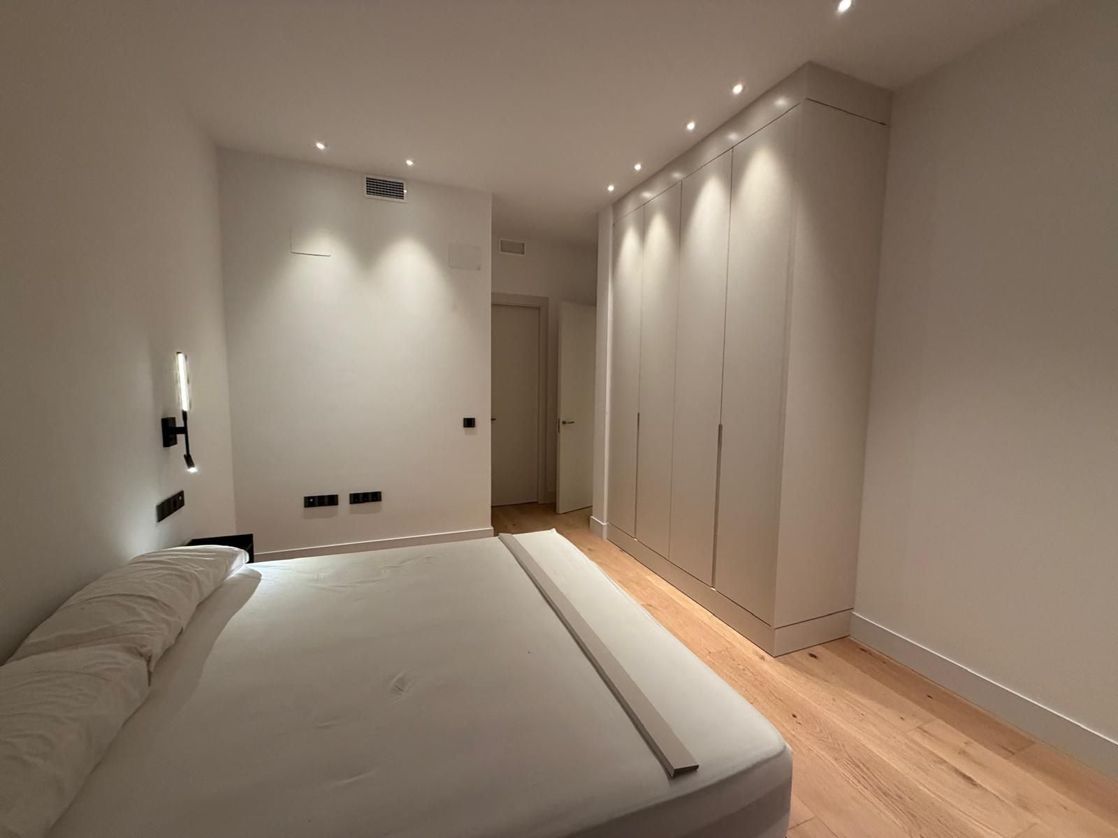 Een slaapkamer met een bed, een kledingkast en een deur naar een andere kamer.