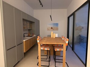 Una cocina moderna con armarios grises, una mesa de comedor de madera y sillas a rayas naranjas.
