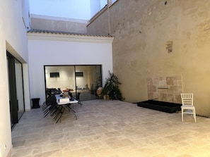 Un patio con una mesa, sillas, una planta en maceta y una silla blanca.