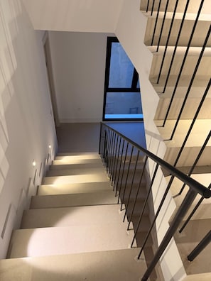 A modern staircase with a metal railing, leading to a landing with a large window. - New Listing (Sanlúcar de Barrameda)