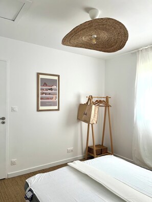 A bedroom with a bed, a hanging light fixture, a coat rack, and a framed picture on the wall. - New Listing (Barneville-Carteret)
