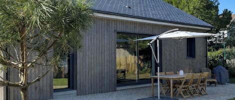 Una casa moderna con un porche cubierto, un comedor y un césped bien cuidado.