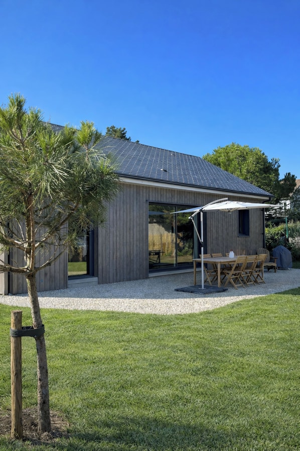 A modern house with a covered patio, a dining area, and a well-maintained lawn. - New Listing (Barneville-Carteret)