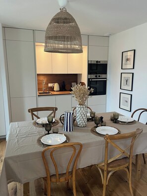 A dining area with a table set for four, surrounded by wooden chairs, a woven pendant light, and framed artwork on the wall. - New Listing (Barneville-Carteret)
