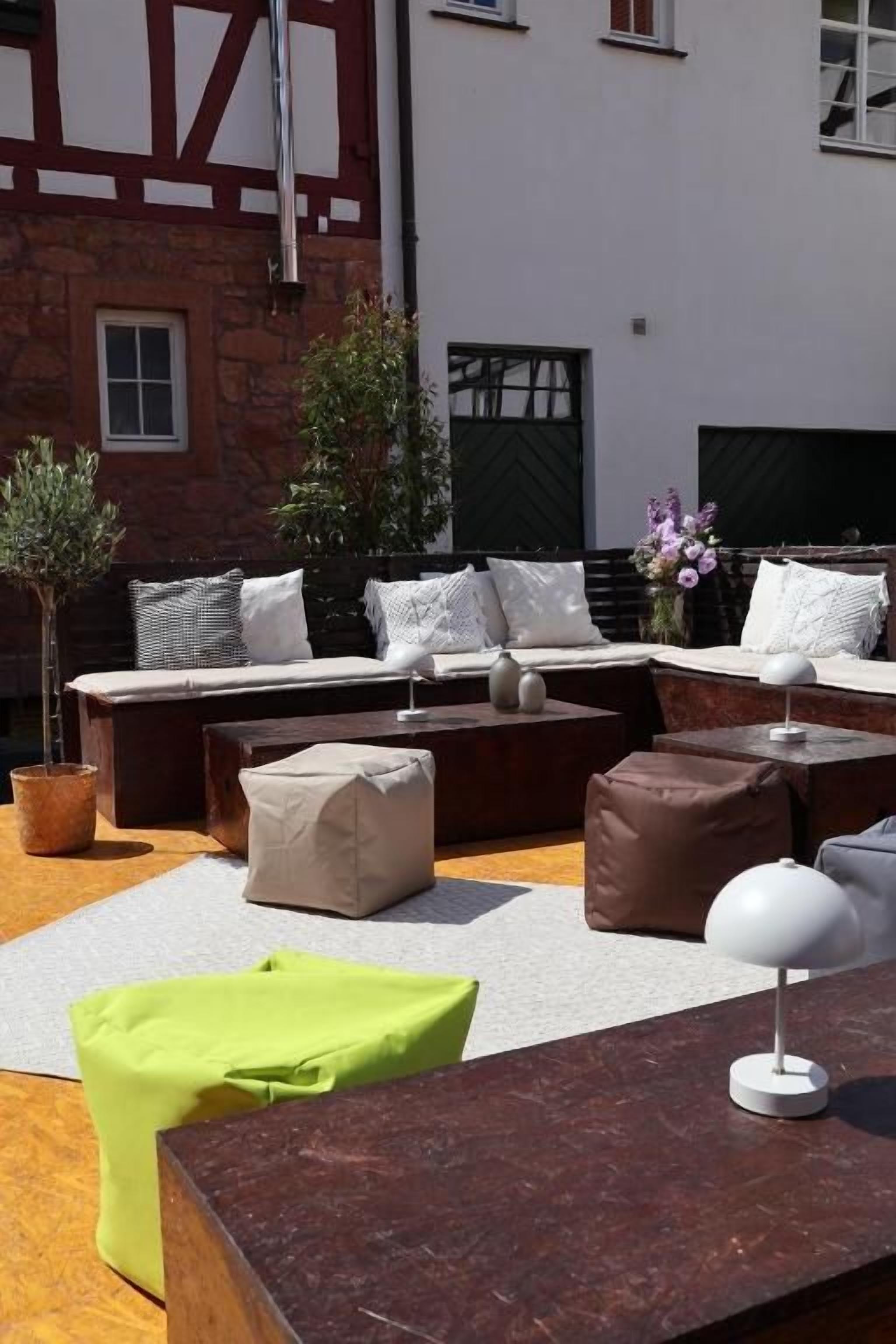 An outdoor seating area with a sofa set, cushions, a table, and a lamp.