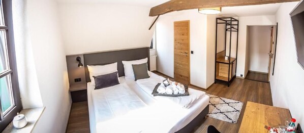 A bedroom with a bed, bedside tables, a wooden wardrobe, and a small table with toiletries.