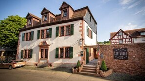 A traditional European building with a stone facade, multiple windows with shutters, and a sign indicating it is a hotel. - Steinhaus1718 (Büdingen)
