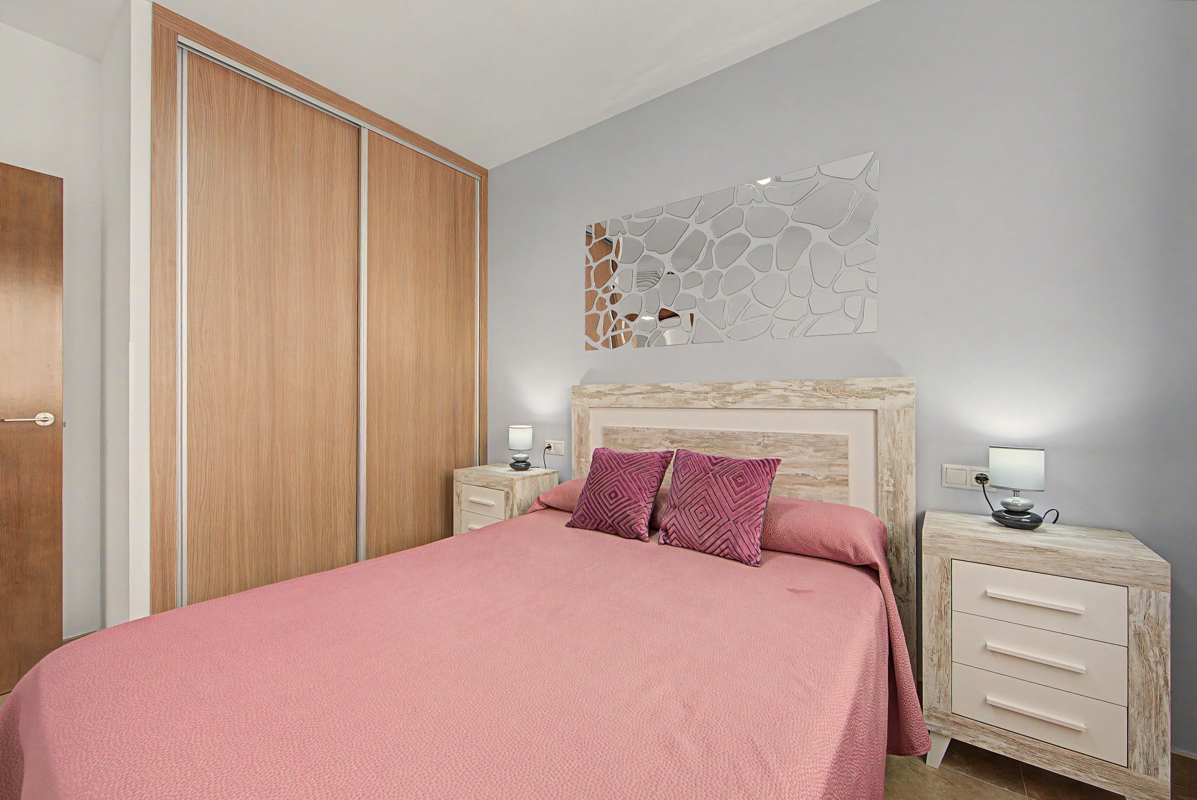Ein Schlafzimmer mit einem Bett, einem Nachttisch, einem Wandbild und einem Kleiderschrank.