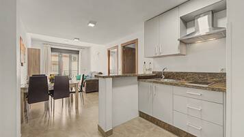 A modern kitchen with white cabinets, a granite countertop, and a stainless steel range hood.