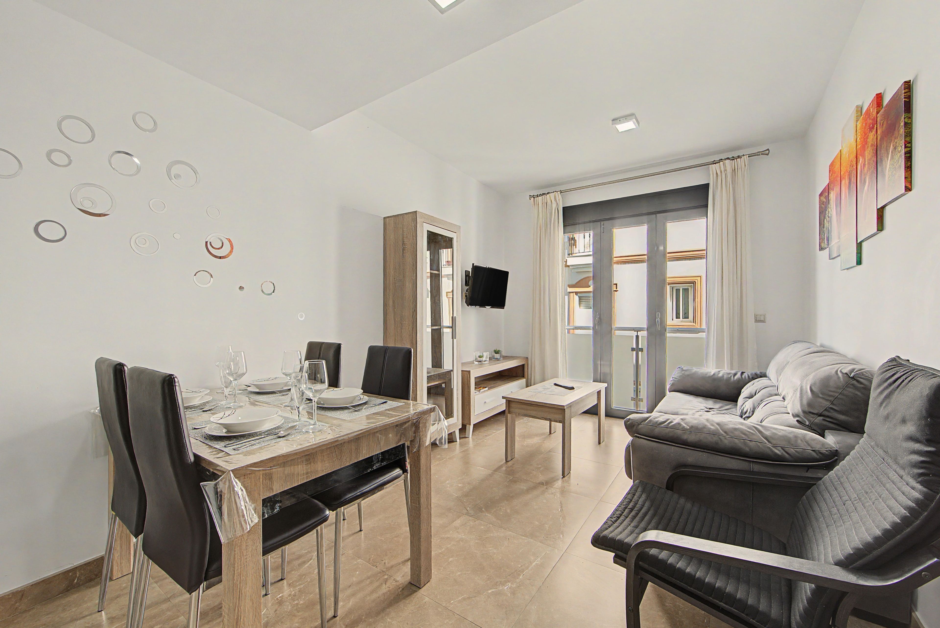 Un salon moderne comprenant un coin repas, un canapé, un téléviseur et une vue sur l’extérieur.