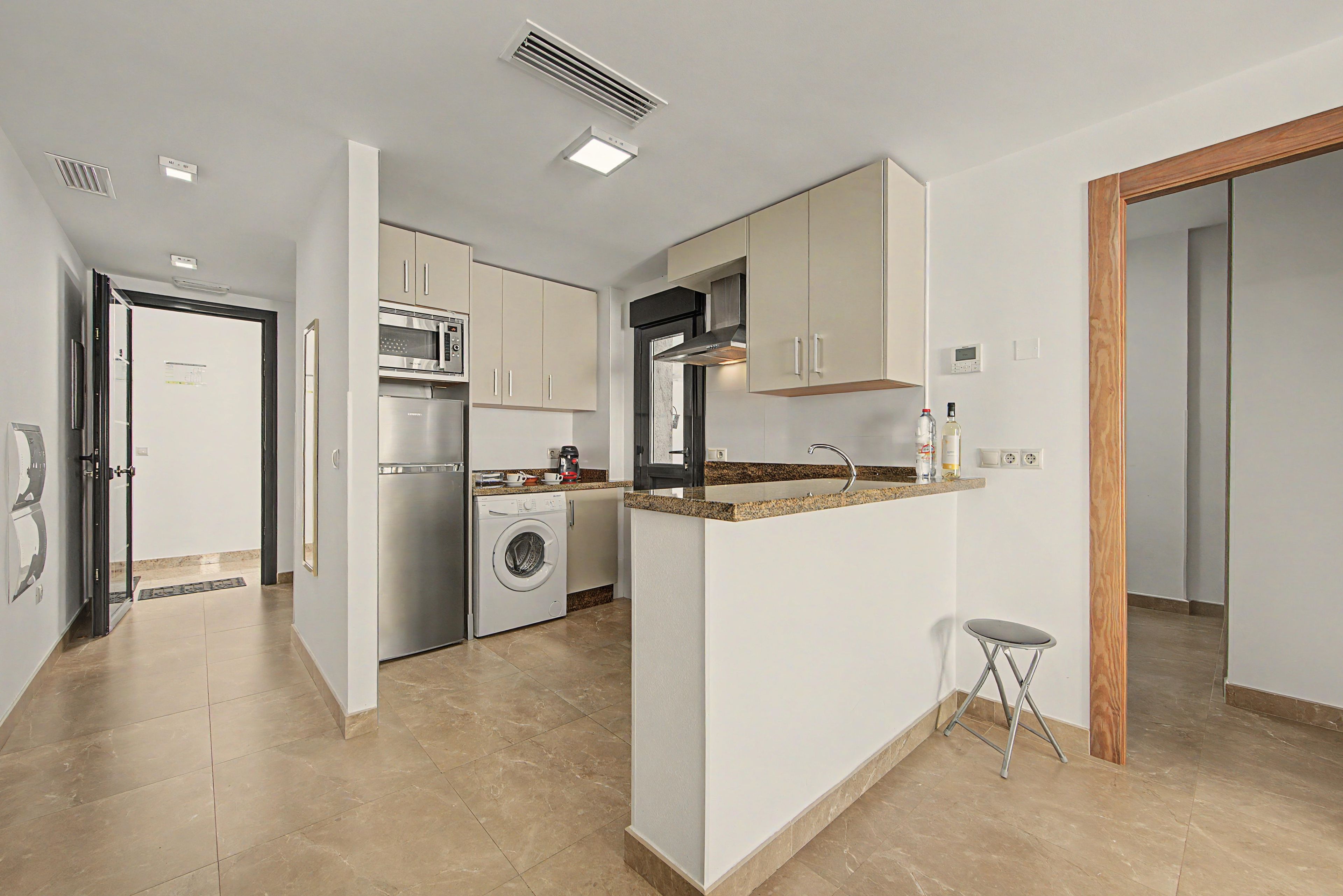 Een moderne keuken met inbouwapparatuur, een centraal eiland en een kleine kruk.