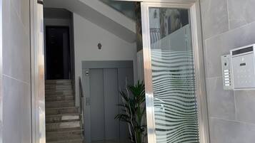 A hotel entrance with a sign reading 'C/AIRE 4', a staircase, a potted plant, and a tiled floor.