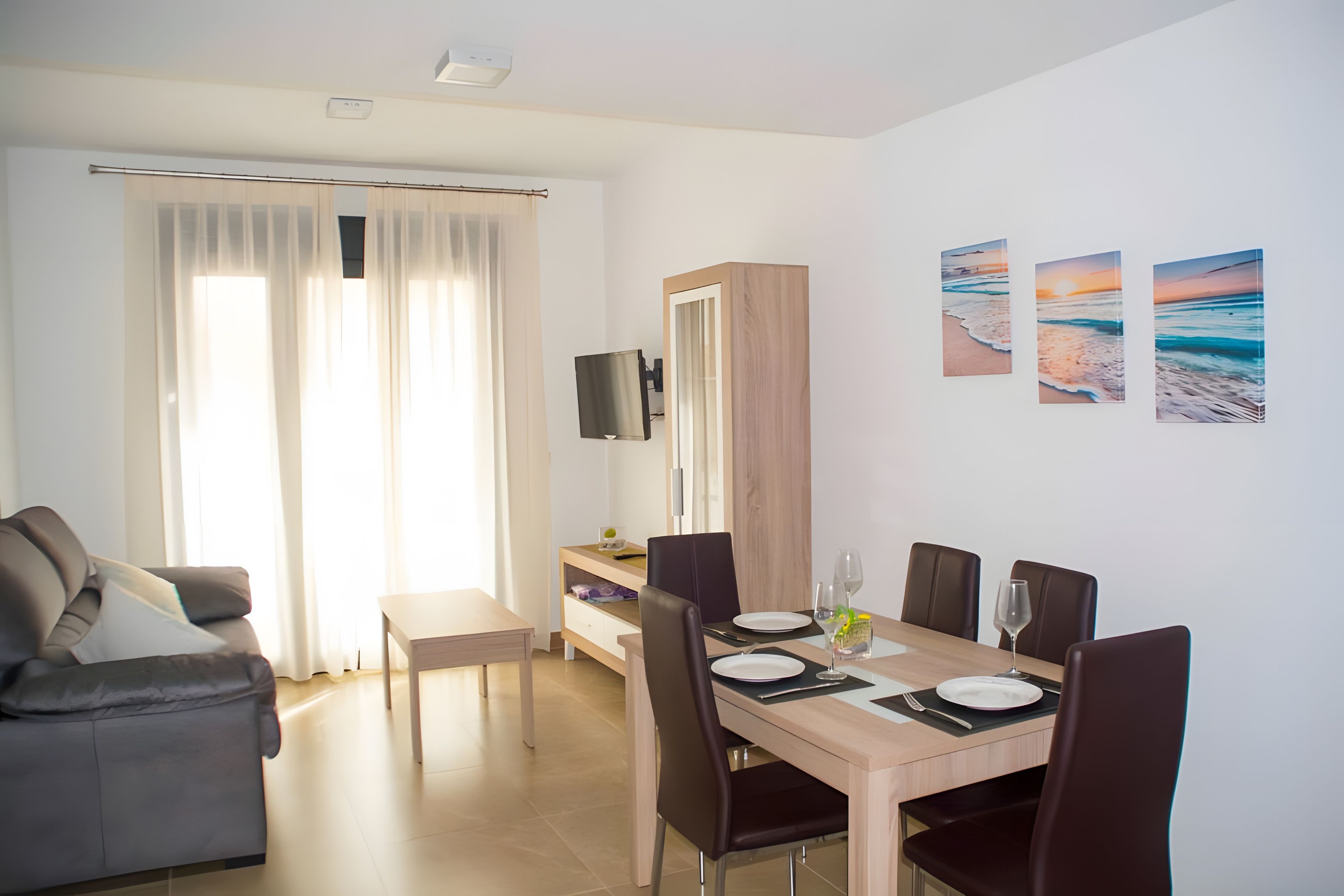 Een moderne eetruimte met een houten tafel, stoelen en een flatscreen televisie aan de wand.